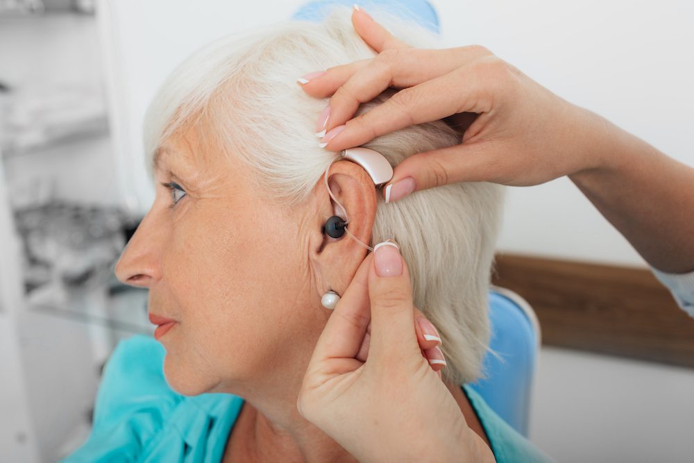 Audiologist fitting a hearing aid for a patient